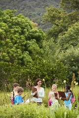 Obraz premium Young teacher with children preparing notes on clipboards during field trip