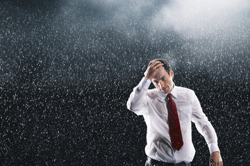Portrait of a young businessman running fingers through wet hair in the rain