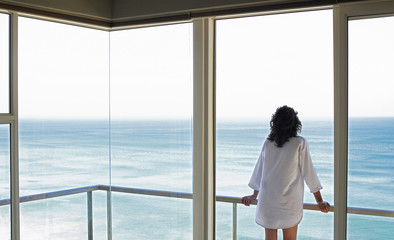 Rear view of young woman looking at sea view from balcony at resort