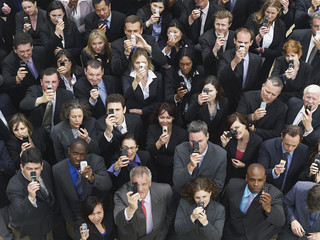 Elevated view of large group of business people taking photographs with mobile phones 