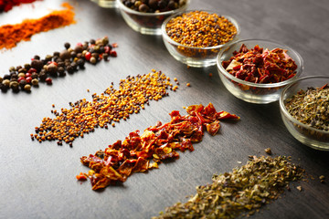 Various spices in glass bowls on grey table