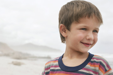 Closeup of cute little boy smiling while looking away at beach