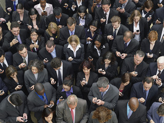 Elevated view of large group of business people text messaging with mobile phones 