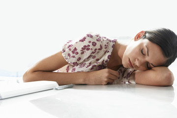 Tired young businesswoman sleeping at office desk