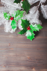 Holly and fir twigs on wood wall