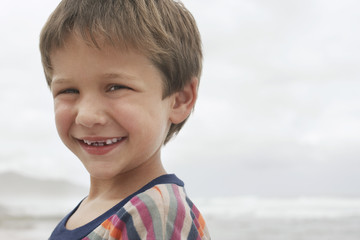 Closeup portrait of happy little boy smiling at beach