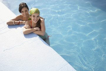 Elevated view of happy teenage girls relaxing at the edge of swimming pool