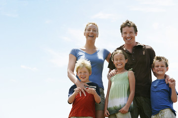 Portrait of happy parents with children standing against sky