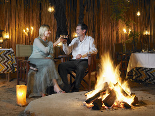 Man and woman toasting at outdoor nightclub near bonfire © MDBPIXS
