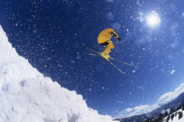 Low angle view of a skier in midair above snow on ski slopes - Powered by Adobe