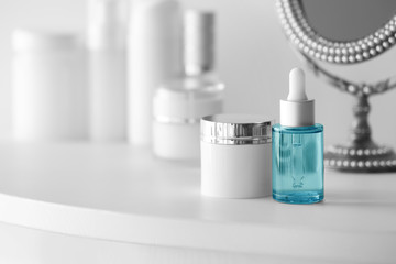 Cream and bottle of perfume on white table, close up view