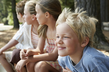 Closeup of young boys and girls sitting in forest