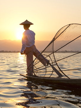 Intha 'leg rowing' fishermen sunset on Inle Lake who row traditional wooden boats using their leg and fish using nets stretched over conical bamboo frames, Inle Lake