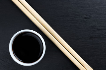 Soy sauce in small white bowl with chopsticks.