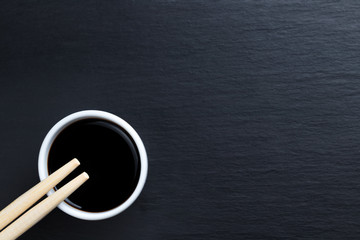 Soy sauce in small white bowl with chopsticks.