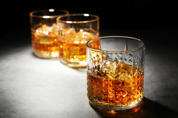 Glasses of whisky on grey textured table closeup