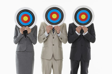 Three businesspeople holding targets in front of faces against white background