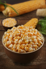 Corn seeds in bowl on wooden table, closeup