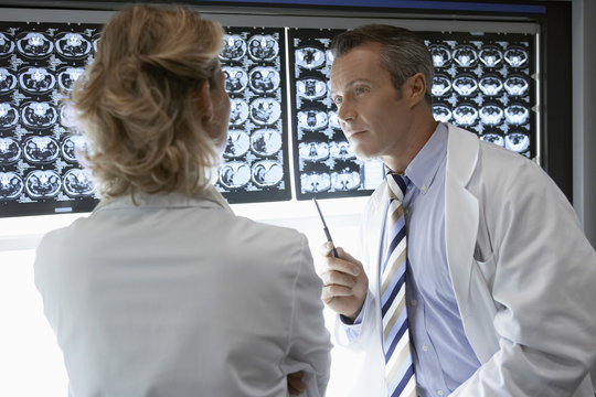 Male and female doctors discussing brain scans in hospital