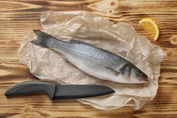 Raw fish with knife on wooden table
