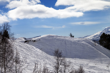 Off-piste slope with traces from skis and snowboards in sun day