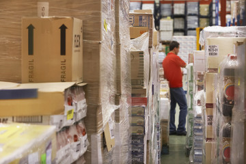 Warehouse full of cellophane wrapped goods with man in the background