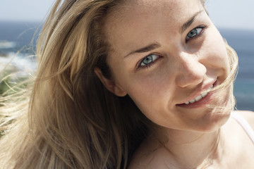 Closeup portrait of a beautiful young woman smiling on beach