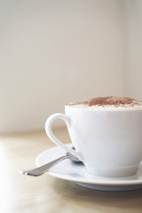 Cappuccino in a porcelain cup on wooden table