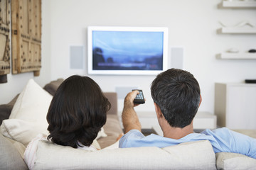 Rear view of couple watching television in living room