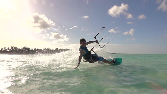 SLOW MOTION: Young surfer man kiteboarding in tropical island lagoon at sunset