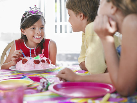 Young Girl With Birthday Cake Talking To Guests At Outdoor Birthday Party