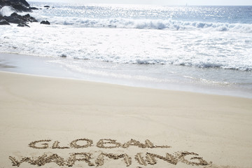 Global warming written in the sand at beach