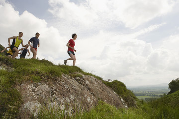 Side view of a group of people running on hill