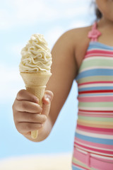 Midsection of girl holding cone icecream on beach