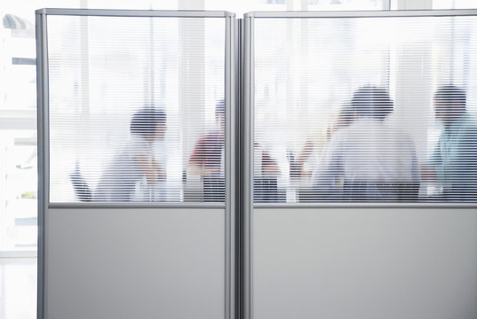 Group of business people in meeting behind translucent wall in office