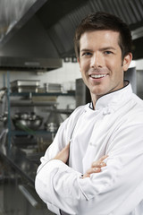 Portrait of a smiling male chef with arms crossed in kitchen