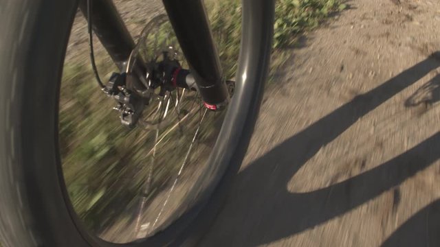 CLOSE UP: Electric offroad bicycle tire wheel spinning fast on gravel path