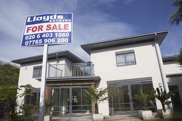 Low angle view of for sale sign outside a new house against the sky