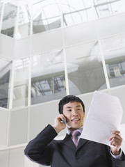 Businessman using mobile phone in atrium of office building