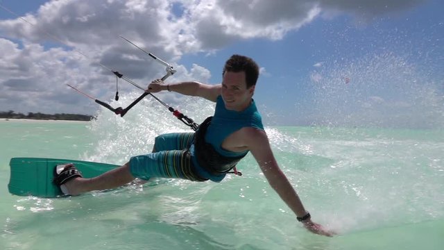 SLOW MOTION: Young kite surfer kiteboarding hand drag past the camera