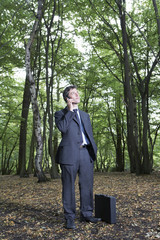 Businessman using mobile phone while standing in forest