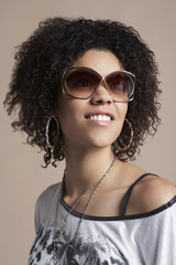 Fashion portrait of beautiful young woman wearing sunglasses on colored background