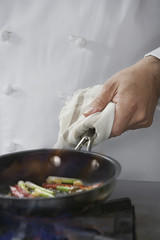 Closeup midsection of a chef cooking food in frying pan