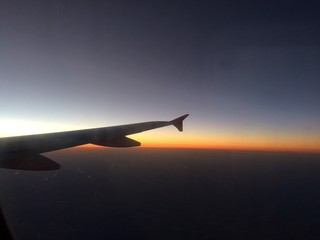 Fototapeta na wymiar The airplane wing in the sunset sky