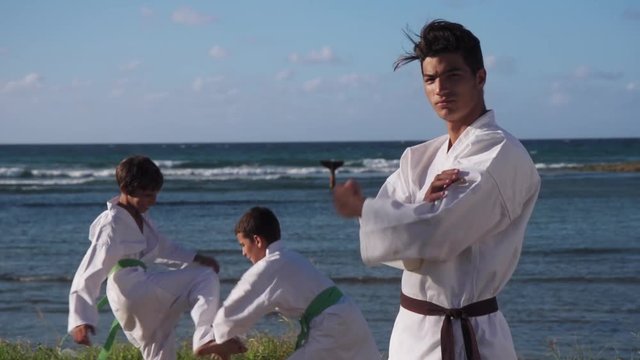 People, children, athletes, sport activity, combat and extreme sports, hispanic men training in karate and traditional martial arts. Simulation of fight near the sea. Portrait of trainer teaching kids