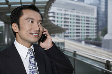 Closeup of handsome businessman using cell phone on footbridge