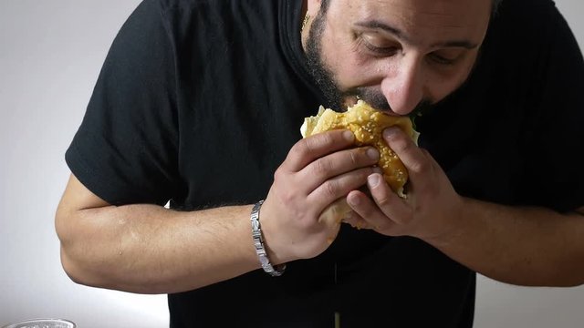 man eating with voracity an XXL hamburger: diet, overweight, obesity, junk food