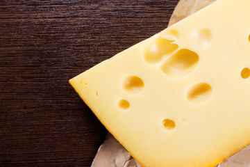 Piece of cheese lies on the dark brown wooden table