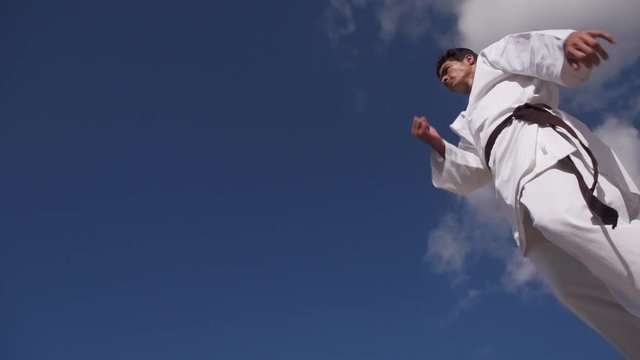 Young people, athlete, sport activity, combat and extreme sports, hispanic man exercising in karate and traditional martial arts, jumping in the sky