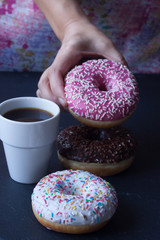 hand holding donut and coffee on a black background